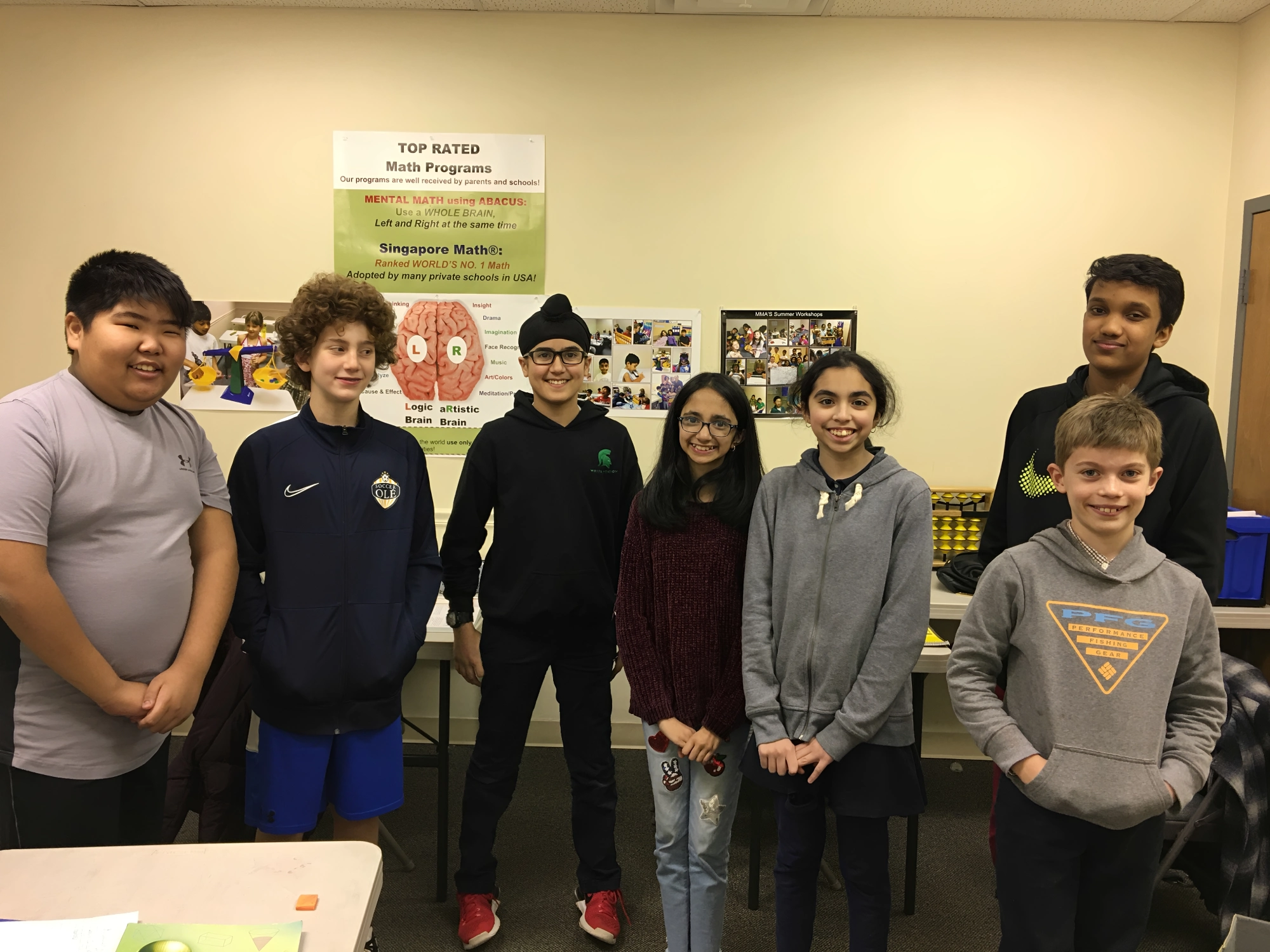 Group of seven smiling students in classroom.