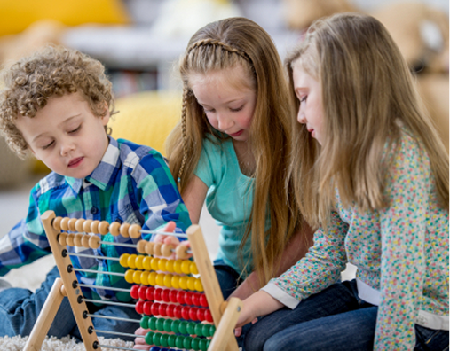 Three children sit together on the floor using a wooden abacus with colorful beads, focused on the activity.