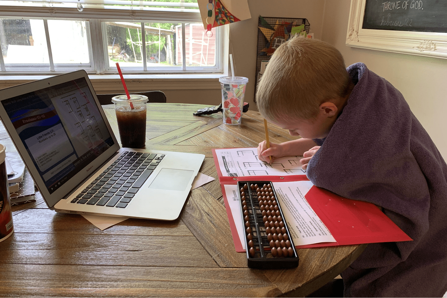 Child studying at home with laptop.